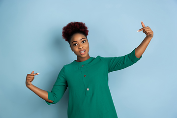 Image showing African-american beautiful young woman\'s portrait on blue studio background, emotional and expressive. Copyspace for ad.