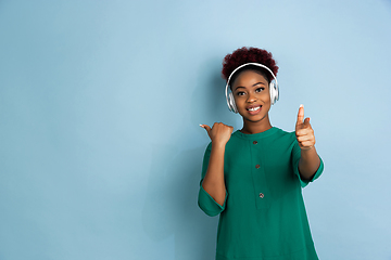 Image showing African-american beautiful young woman\'s portrait on blue studio background, emotional and expressive. Copyspace for ad.