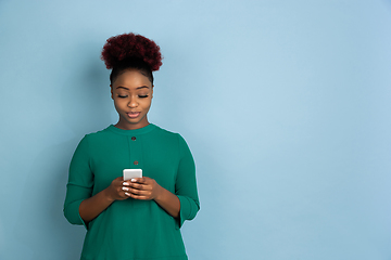 Image showing African-american beautiful young woman\'s portrait on blue studio background, emotional and expressive. Copyspace for ad.