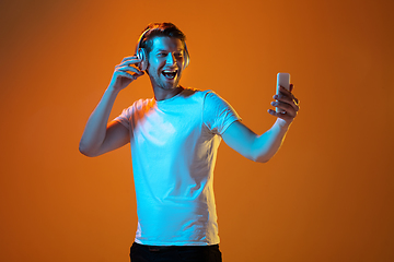 Image showing Caucasian beautiful young man\'s portrait on gradient orange studio background, emotional and expressive. Copyspace for ad.