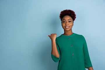 Image showing African-american beautiful young woman\'s portrait on blue studio background, emotional and expressive. Copyspace for ad.