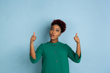 Image showing African-american beautiful young woman\'s portrait on blue studio background, emotional and expressive. Copyspace for ad.