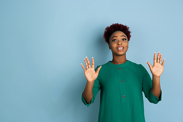 Image showing African-american beautiful young woman\'s portrait on blue studio background, emotional and expressive. Copyspace for ad.