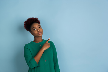 Image showing African-american beautiful young woman\'s portrait on blue studio background, emotional and expressive. Copyspace for ad.