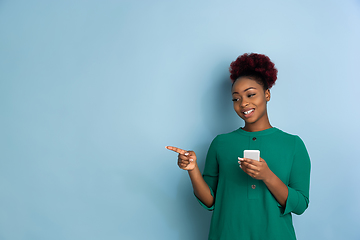 Image showing African-american beautiful young woman\'s portrait on blue studio background, emotional and expressive. Copyspace for ad.