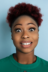 Image showing African-american beautiful young woman\'s close up portrait on blue studio background, emotional and expressive. Copyspace for ad.