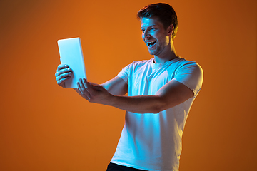 Image showing Caucasian beautiful young man\'s portrait on gradient orange studio background, emotional and expressive. Copyspace for ad.