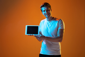 Image showing Caucasian beautiful young man\'s portrait on gradient orange studio background, emotional and expressive. Copyspace for ad.