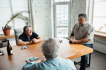 Image showing Group of happy mature friends playing cards and drinking wine