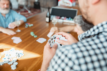 Image showing Close up group of happy mature friends playing cards and drinking wine