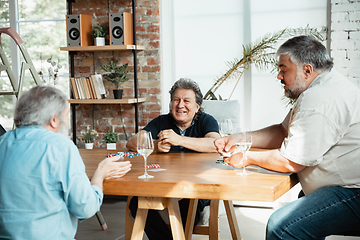 Image showing Group of happy mature friends playing cards and drinking wine