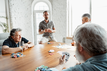 Image showing Group of happy mature friends playing cards and drinking wine