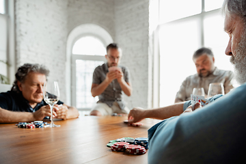 Image showing Group of happy mature friends playing cards and drinking wine
