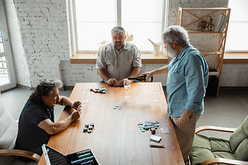 Image showing Group of happy mature friends playing cards and drinking wine