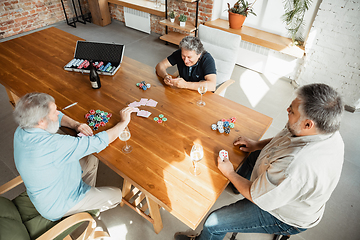 Image showing Group of happy mature friends playing cards and drinking wine