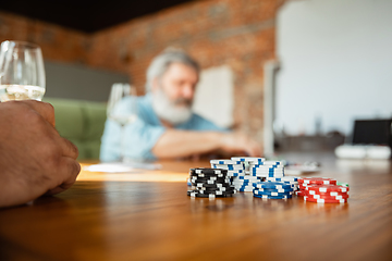 Image showing Close up group of happy mature friends playing cards and drinking wine