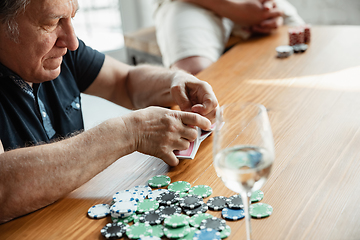 Image showing Senior man playing cards and drinking wine with friends, looks happy