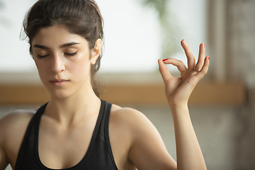 Image showing Sporty young muslim woman taking yoga lessons online and practice at home, close up