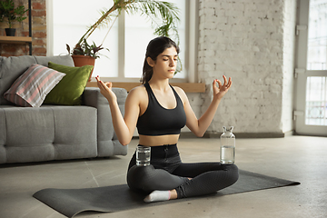 Image showing Sporty young muslim woman taking yoga lessons online and practice at home