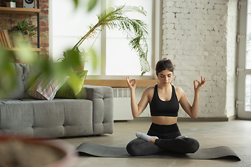 Image showing Sporty young muslim woman taking yoga lessons online and practice at home