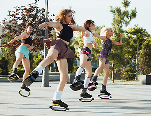 Image showing Beautiful women in sportswear jumping in a kangoo jumps shoes at the street on summer\'s sunny day