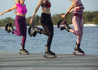 Image showing Beautiful women in sportswear jumping in a kangoo jumps shoes at the street on summer\'s sunny day