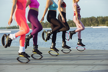 Image showing Beautiful women in sportswear jumping in a kangoo jumps shoes at the street on summer\'s sunny day