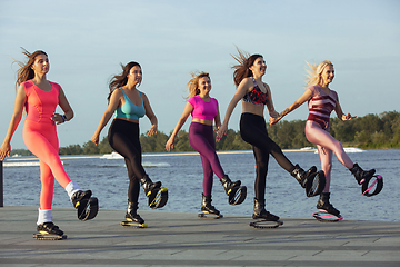 Image showing Beautiful women in sportswear jumping in a kangoo jumps shoes at the street on summer\'s sunny day