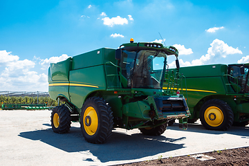 Image showing Tractor, combine at a field in sunlight. Confident, bright colors