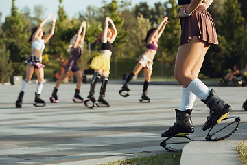 Image showing Beautiful women in sportswear jumping in a kangoo jumps shoes at the street on summer\'s sunny day