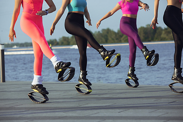 Image showing Beautiful women in sportswear jumping in a kangoo jumps shoes at the street on summer\'s sunny day