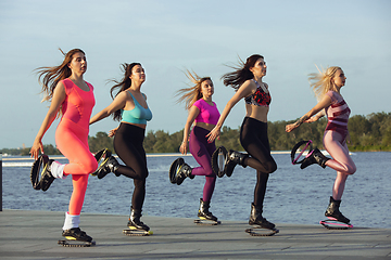 Image showing Beautiful women in sportswear jumping in a kangoo jumps shoes at the street on summer\'s sunny day