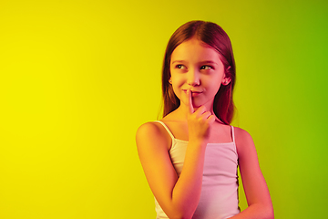 Image showing Little caucasian girl\'s portrait isolated on gradient background in neon light. Concept of human emotions, facial expression, modern gadgets and technologies. Copyspace.