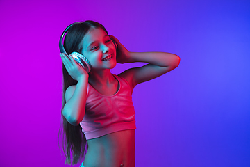 Image showing Little caucasian girl\'s portrait isolated on gradient pink-blue background in neon light.