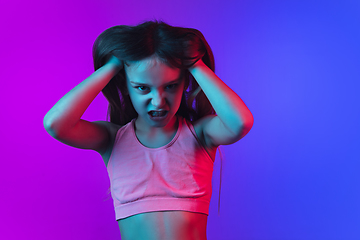 Image showing Little caucasian girl\'s portrait isolated on gradient pink-blue background in neon light.