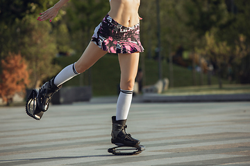 Image showing Beautiful woman in sportswear jumping in a kangoo jumps shoes at the street on summer\'s sunny day