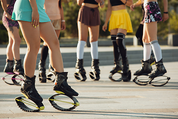 Image showing Beautiful women in sportswear jumping in a kangoo jumps shoes at the street on summer\'s sunny day