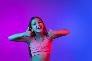 Image showing Little caucasian girl\'s portrait isolated on gradient pink-blue background in neon light.