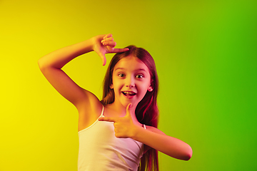 Image showing Little caucasian girl\'s portrait isolated on gradient background in neon light. Concept of human emotions, facial expression, modern gadgets and technologies. Copyspace.