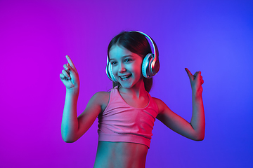 Image showing Little caucasian girl\'s portrait isolated on gradient pink-blue background in neon light.