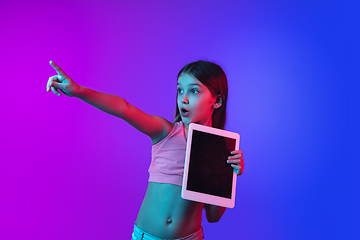 Image showing Little caucasian girl\'s portrait isolated on gradient pink-blue background in neon light.