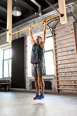 Image showing man exercising on bar and doing pull-ups in gym