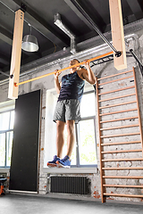 Image showing man exercising on bar and doing pull-ups in gym