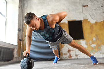 Image showing young man doing kettlebell push-ups in gym