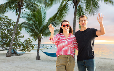 Image showing happy couple waving hands on beach