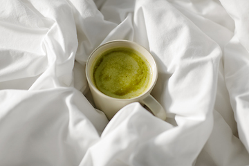 Image showing cup of matcha tea in bed at home