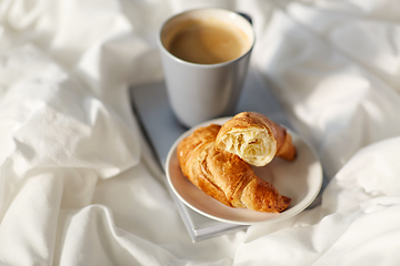 Image showing croissants, cup of coffee and book in bed at home