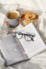 Image showing croissants, cup of coffee, book and glasses in bed