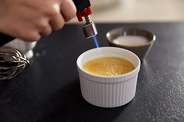 Image showing hand with burner making sugar crust in baking dish