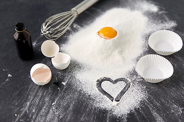 Image showing flour, egg, whisk and paper baking molds on table